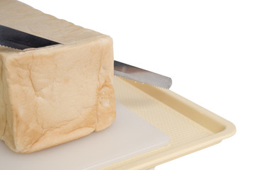 View of a loaf of homemade bread and a slice on a wooden breadboard with a bread knife