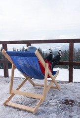 Person at mountains in winter sit on sun-lounger