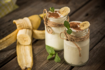 Organic homemade sweet milk dessert with banana, cinnamon and mint on the wooden table