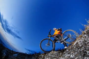 Fototapeta na wymiar Cyclist Riding the Bike Down Hill on the Mountain Rocky Trail at Sunset. Extreme Sports