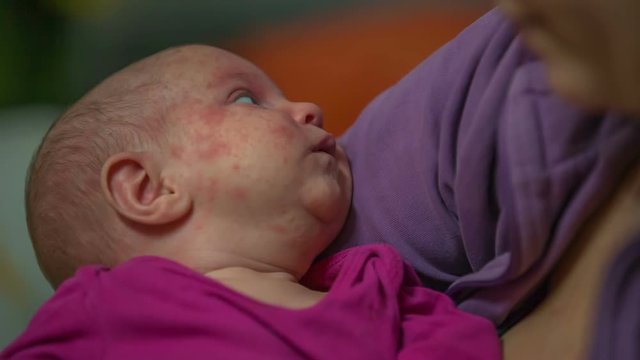 A small baby girl is lying in her mother's arms very peacefully. She is not crying or anything.
