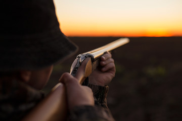 Hunter aiming shotgun in dusk