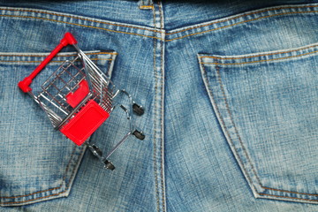 Shopping cart put on the jean pocket surface as a background represent the shopping and apparel concept related idea.