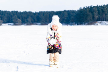 Fototapeta na wymiar Little girl throwing snow in the winter in nature