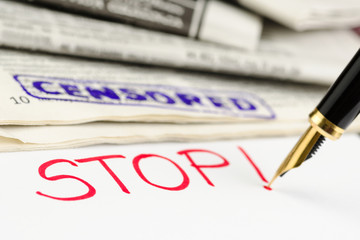 Macro shot of censored stamp, pen and newspaper.