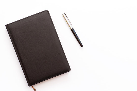 black diary and pen on a white background