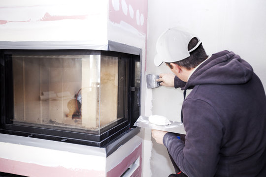Construction worker imposes a finishing coat on fire. Finishing the fireplace. Putting plaster.