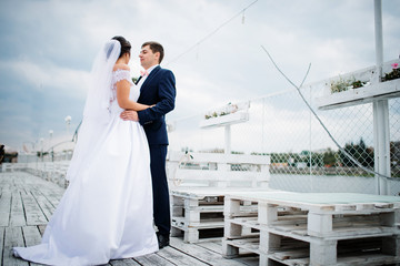 Wedding couple stay on the pier berth at cloudy day.
