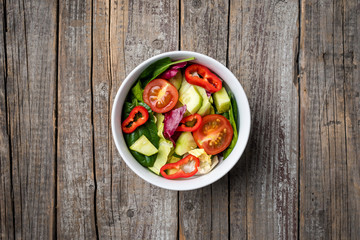 Vegetables salad in white bowl on an old wooden table