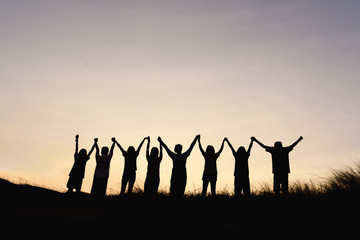 Silhouette of happy team making high hands in sunset sky background