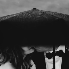 bride and groom kissing under an umbrella in the rain