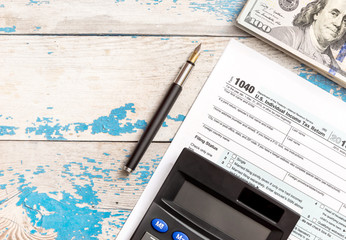 Money, calculator and tax form on the old blue table. Business concept.
