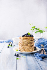 Stack of homemade pancakes with fresh blueberries on a wooden background. Healthy breakfast concept with copy space.