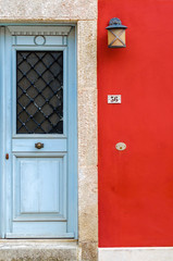 old blue wooden door in composition with a vivid red painted wall. A beautiful combination of colours in a building located in the traditional colorful and awarded village of Crete, Archanes.