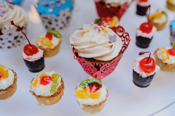 Obraz na płótnie Canvas sweet cupcakes with cherry, kiwi, orange