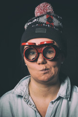 Young girl doing funny faces in red glasses and a cap