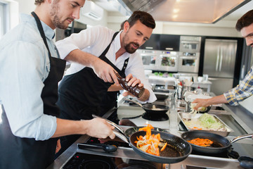 Chefs cooking food at kitchen.