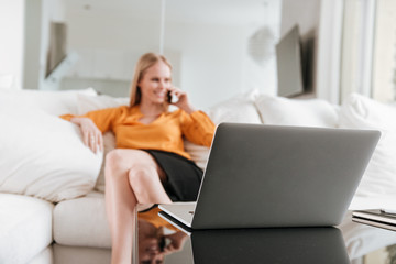 Business woman sitting in office talking by phone