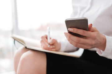 Attractive business woman sitting in office using mobile