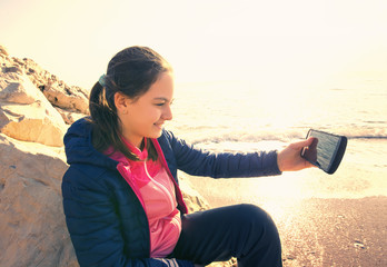 Girl holding the phone an make selfie  at the sea in winter conditions