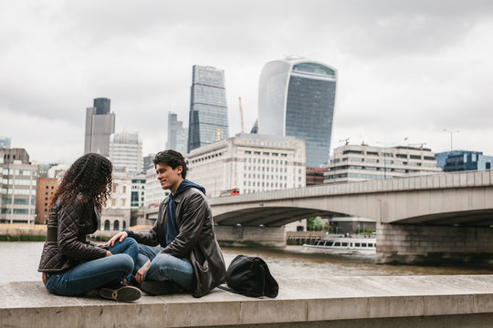 Multi-ethnic couple sitting in the River Thames pier