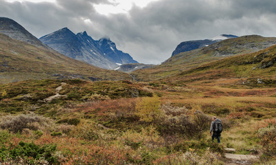 Fototapeta na wymiar Man walks towards the mountains of Hurrungane in Jotunheimen, Norway