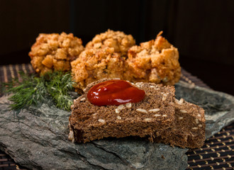 Homemade meat cutlets in batter with parsley, ketchup and bread on stone