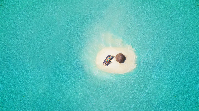 Young woman sunbathing on tiny sandy island