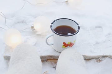 Obraz na płótnie Canvas Coffee mug and Christmas lights in snow