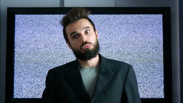 Crazy bearded businessman making funny faces with large grainy screen on the background.