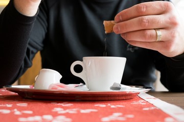 Man putting sugar into his espresso coffee