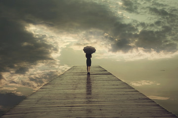 mysterious woman with umbrella crosses a bridge to the threatening sky