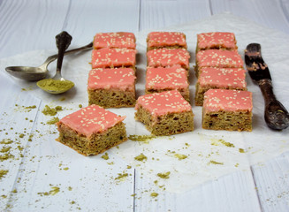 Green cakes with Japanese tea matcha covered chocolate pink frosting on light wooden background. Selective focus. Copy space