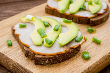 Toast with ham, slices of avocado and green onion