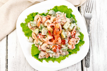 Salad with shrimp and avocado in plate on board top