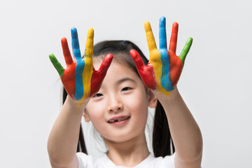 Little Asian girl with hands painted in colorful paints