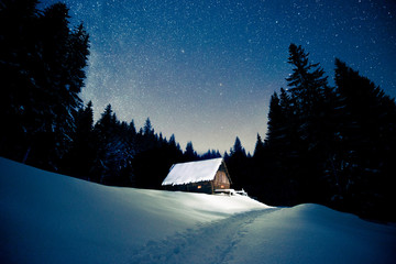 Beautiful wooden house in the winter forest under the stars