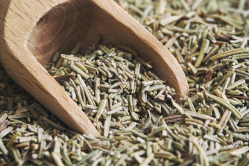 Closeup of dried rosemary leaves with wooden scoop