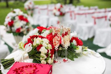 The champagne glasses. Wedding ceremony outdoors. Bouquet with red flowers.