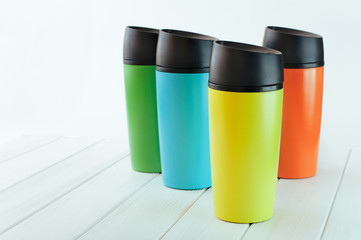 Color thermos mugs on the white wooden table