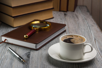 Closed notebook with a fountain pen on rustic table. Magnifying glass on a notepad.
