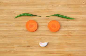 Funny face made of vegetables on wooden block background