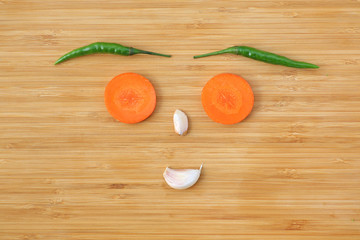 Funny face made of vegetables on wooden block background