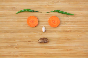 Funny face made of vegetables on wooden block background