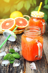 Fototapeta na wymiar Grapefruit juice in two glass jar, open-air drink. Toned image