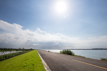 empty road near river in blue sunny sky