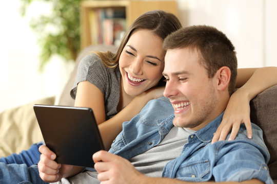 Couple laughing watching content in a tablet