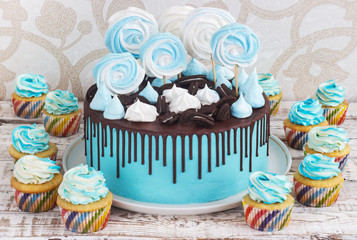 Children's blue cake and cupcakes rainbow color on a white background with meringue
