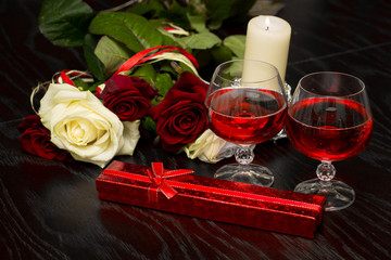 Roses, glasses of wine and a box with a jewel in the light of candles