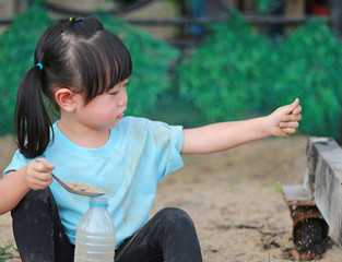 Cute little girl playing in garden with soil